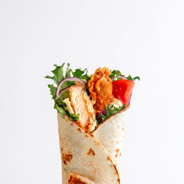 Fried chicken wrap with fresh lettuce, red onion, tomato, and creamy sauce.